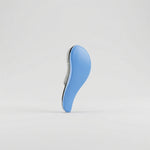 Brosse de toilettage ergonomique bleu ciel posée verticalement, équipée de picots souples noirs pour un démêlage efficace et doux du poil des animaux.