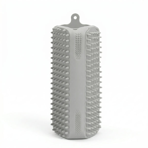 Brosse rectangulaire en silicone gris avec picots souples sur toutes les faces et attache de suspension, conçue pour le brossage des animaux et le retrait des poils.