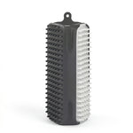 Brosse rectangulaire en silicone noir avec des picots souples noirs et une face de picots blancs, munie d'une attache pour un rangement facile.
