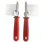 Paire de peignes démêleurs râteaux pour animaux avec dents longues en métal et manches ergonomiques rouges, idéal pour retirer les nœuds et le sous-poil, fond blanc.