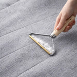 Brosse anti peluches en métal utilisée sur un canapé pour retirer efficacement les poils et peluches incrustés