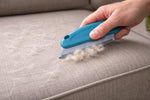 Brosse anti-poils pour animaux en action retirant les poils sur un canapé en tissu facilement