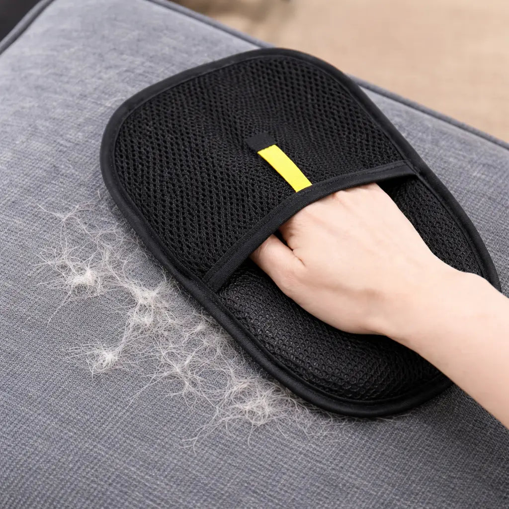 Gant anti poils utilisé sur un canapé pour retirer facilement les poils d’animaux et nettoyer les surfaces textiles sans effort